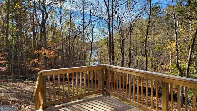 Wooden deck overlooking a wooded backyard with autumn leaves.