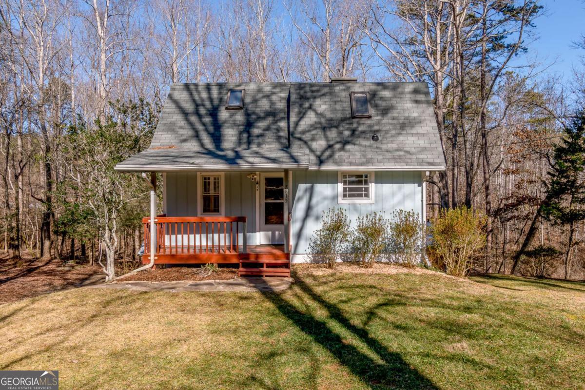 House with a steep gray roof, two skylights, and a red-orange front porch among leafless trees.