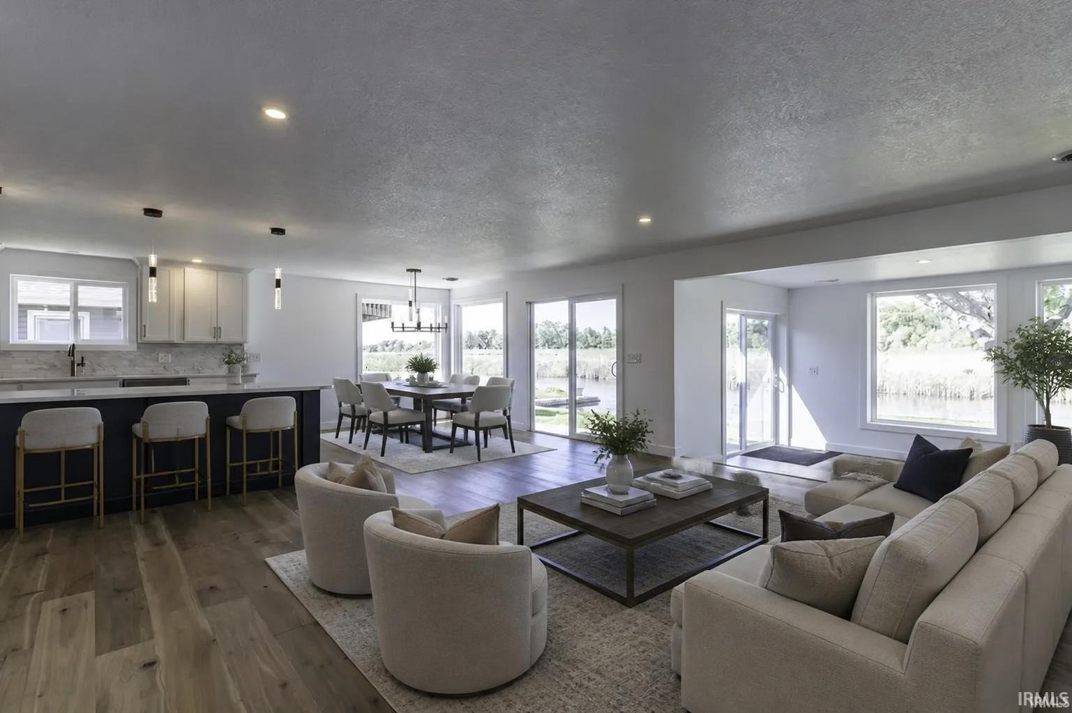 Open-concept living room, dining area, and kitchen with large windows overlooking the water.