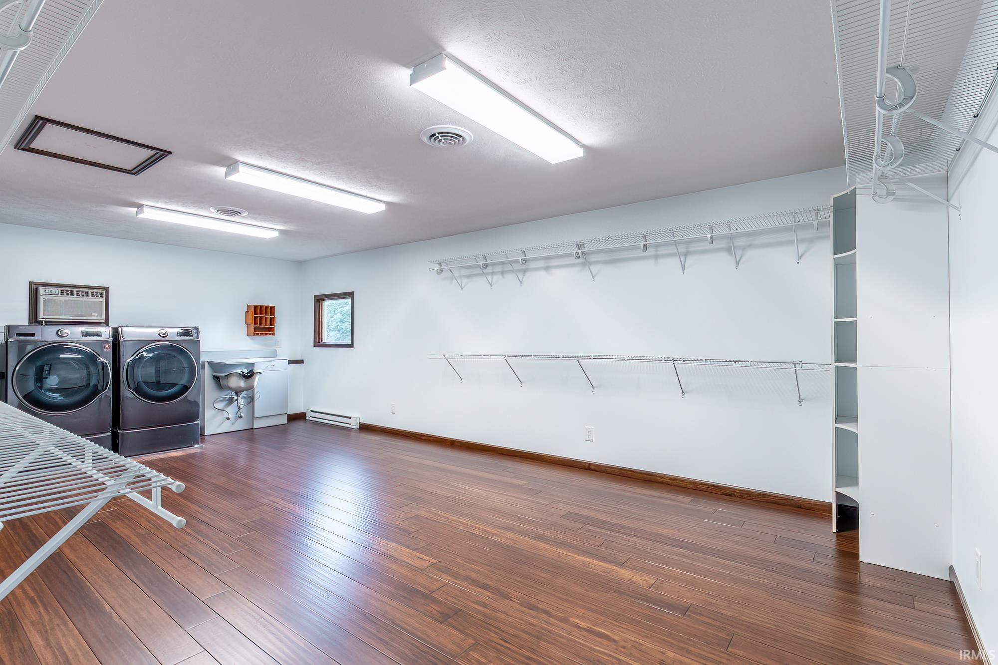 Spacious laundry room with front-loading washer and dryer, utility sink, and extensive wire drying racks.
