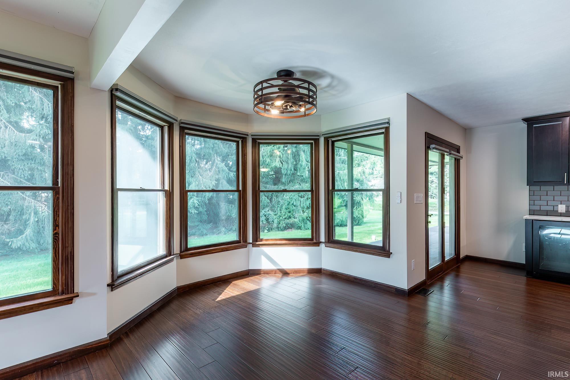 Unfurnished dining area with dark hardwood floors and a curved bay of large windows.