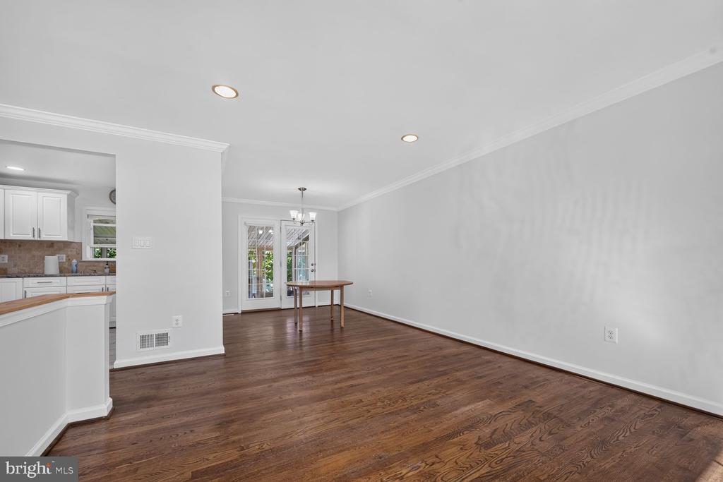 Open dining area with dark hardwood floors, French doors, and a view into the kitchen.