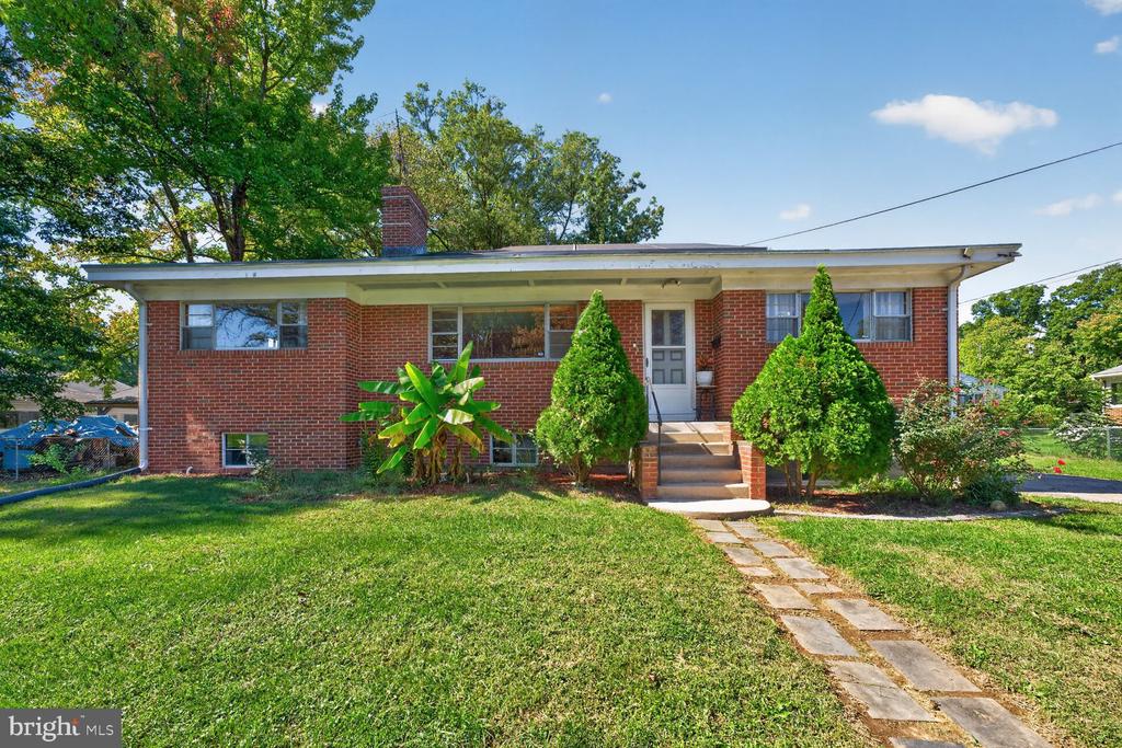 Single-story brick house with front steps, a stone walkway, and a broad green lawn.
