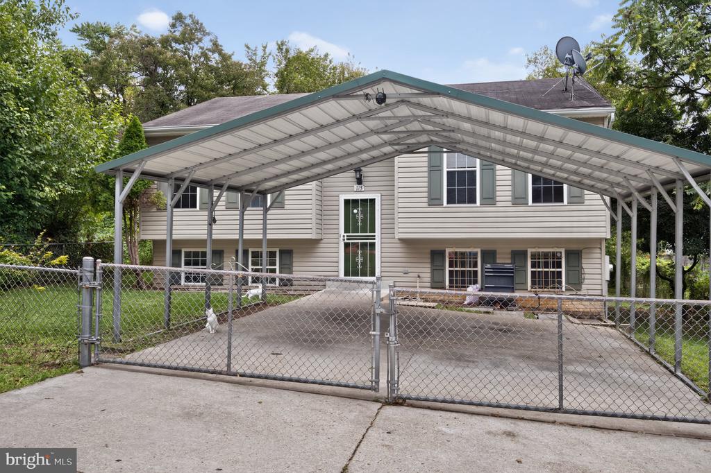 Split-level house with a large metal carport and fenced driveway.