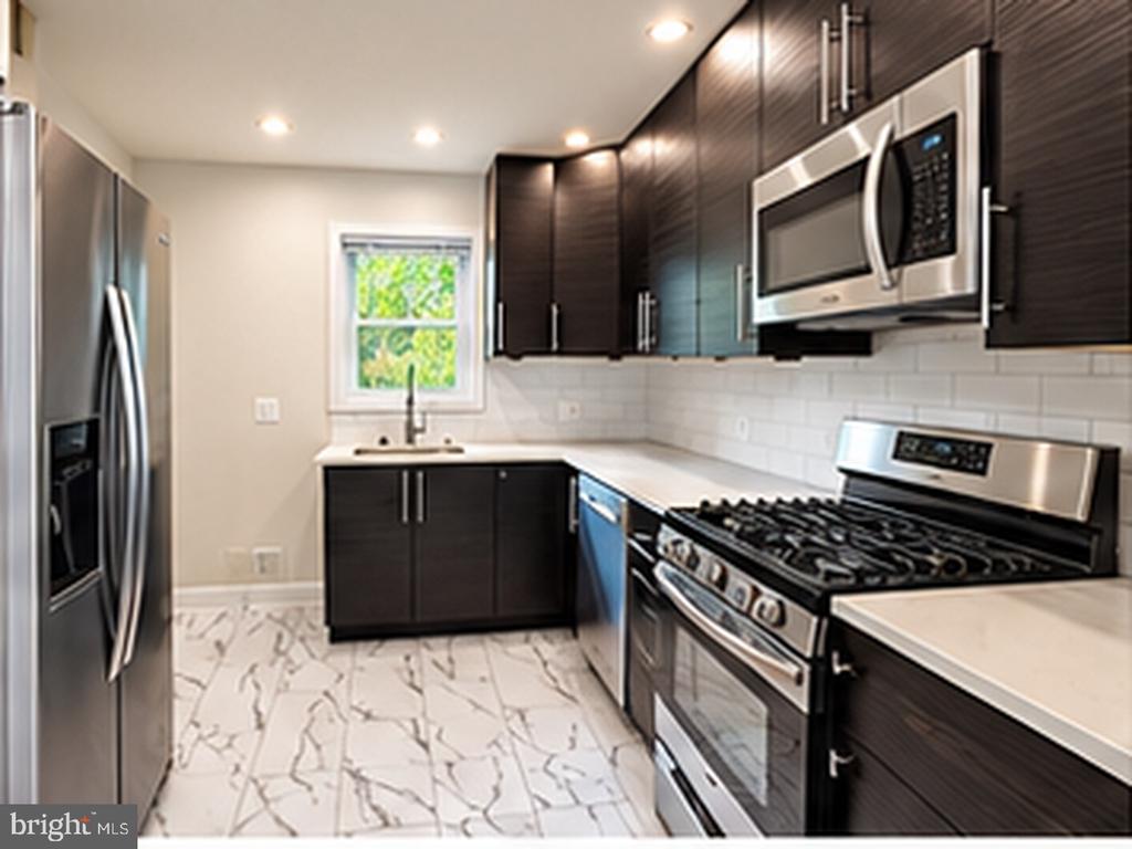 Modern kitchen with dark cabinets, stainless steel appliances, and marble-patterned flooring.