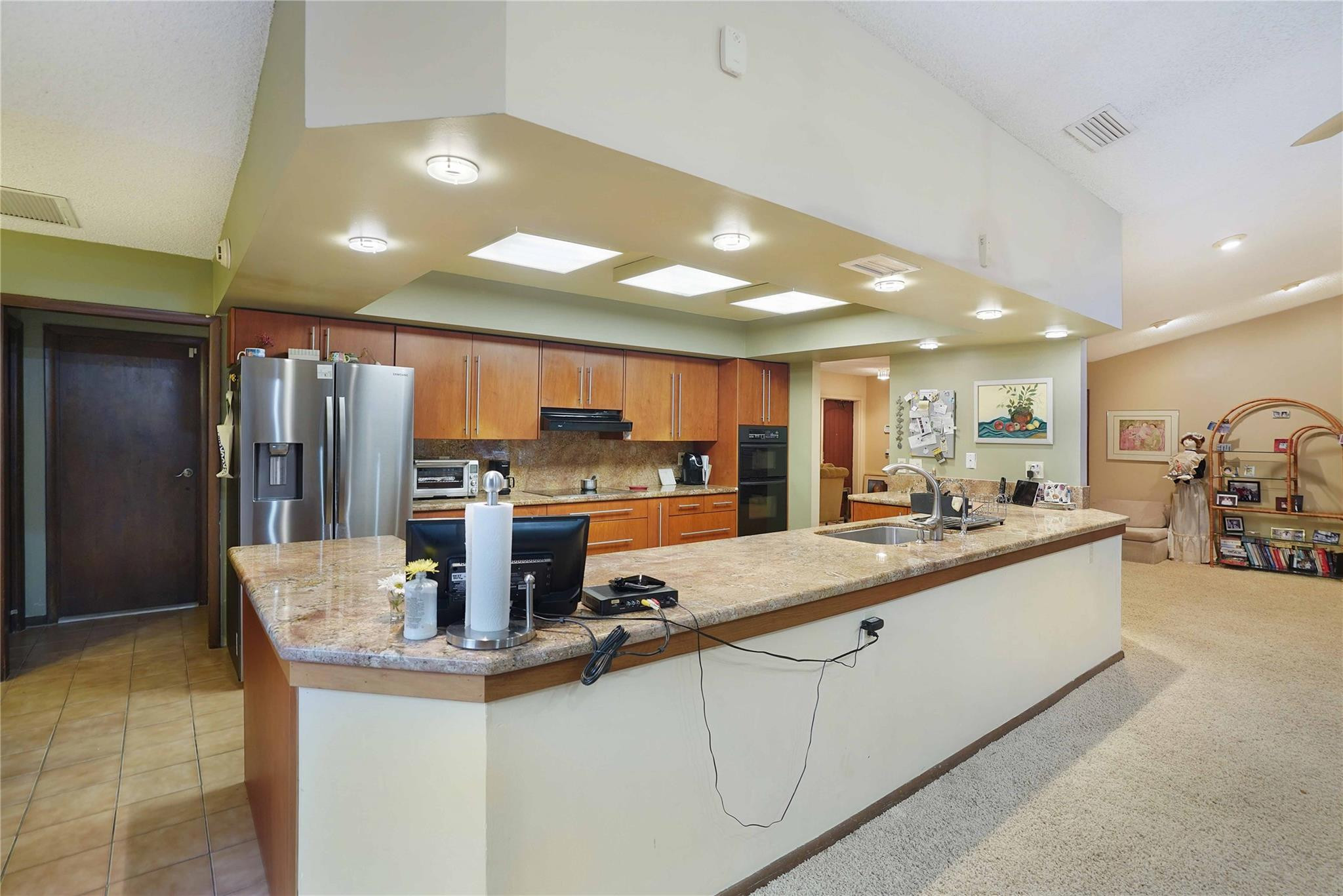 Kitchen with warm wood cabinets, stainless steel appliances, and a large stone-topped island.
