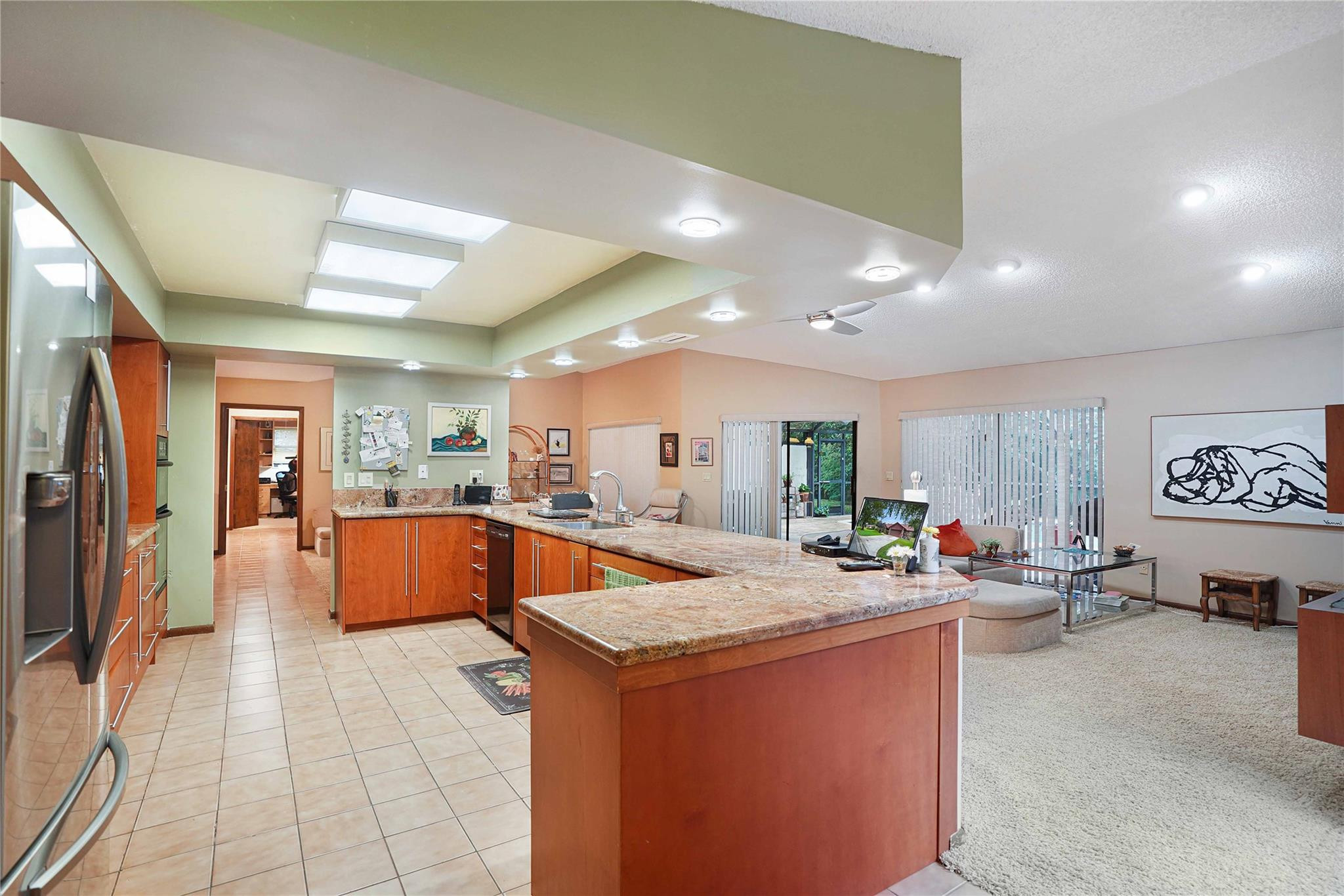 Open kitchen with granite island and adjoining carpeted living area.