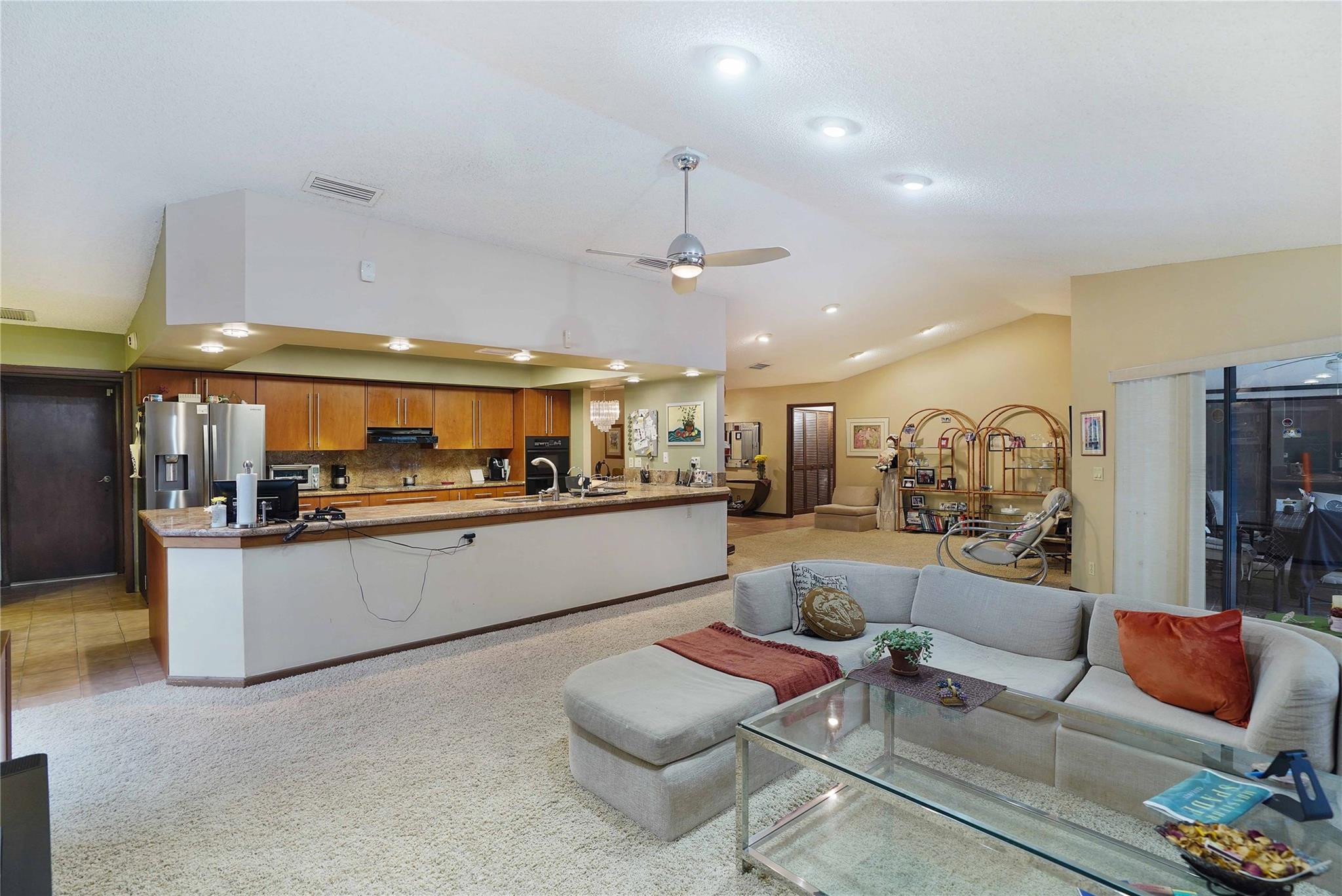 Open-plan kitchen and living room with a large breakfast bar and gray sectional sofa.