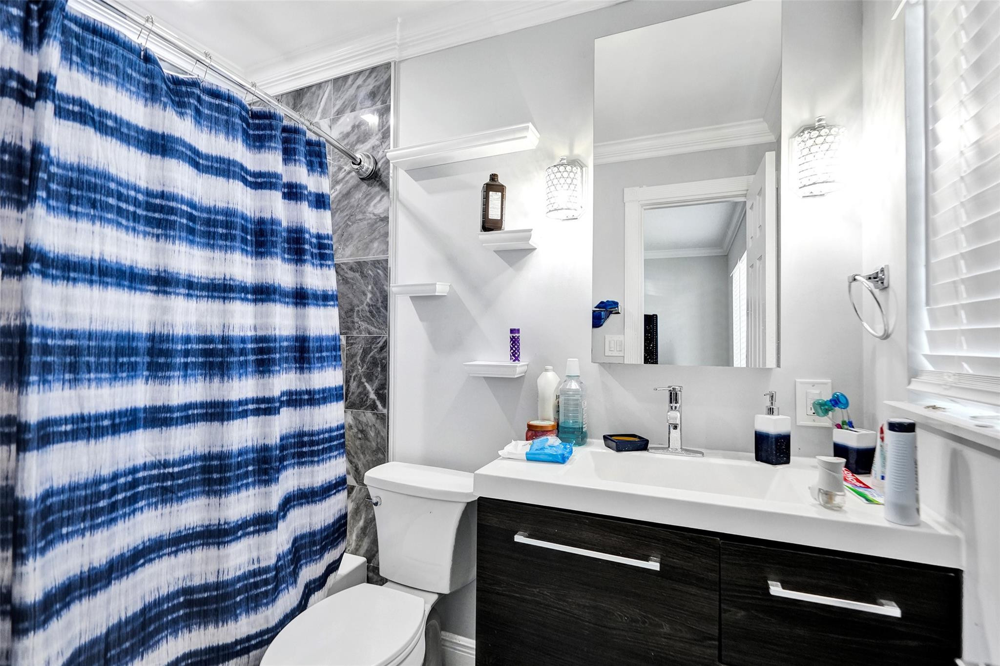 Bathroom with a blue-and-white striped shower curtain and dark wood vanity.