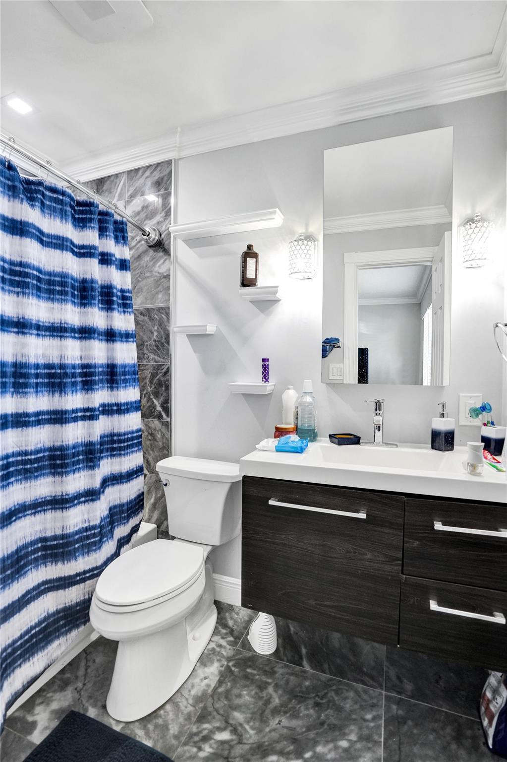 Bathroom with a dark wood vanity, gray tile, and a blue-and-white striped shower curtain.