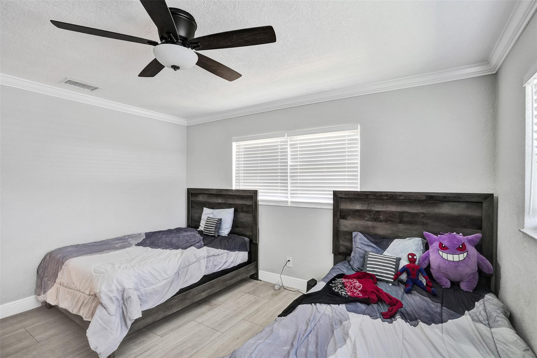 Bedroom with two dark wood beds, gray bedding, and plush character toys on one bed.