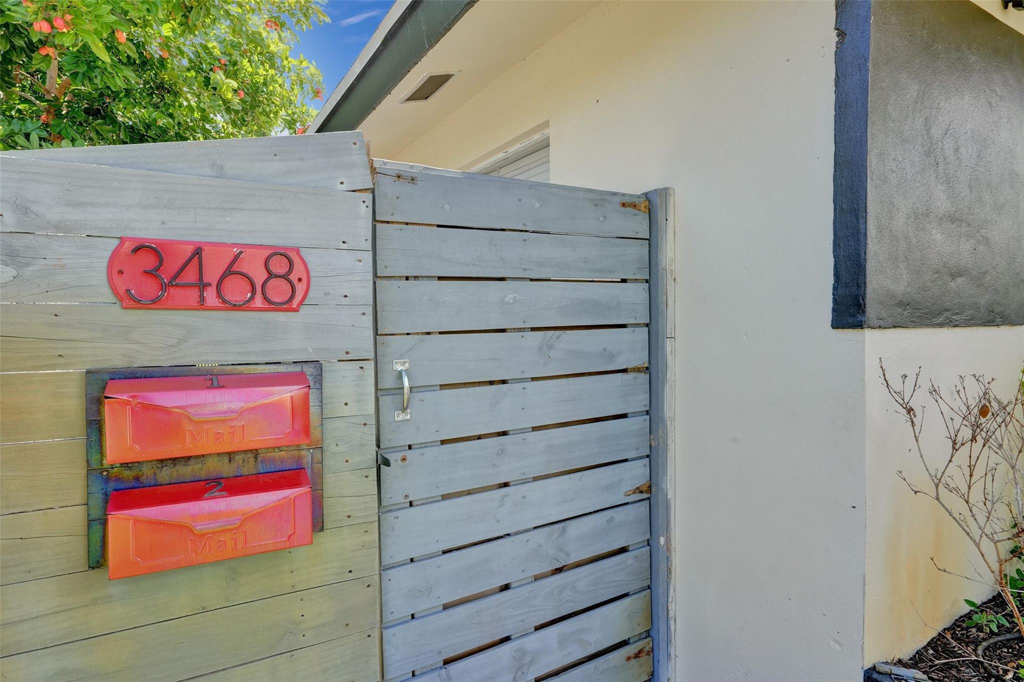 Property entrance with a gray slatted gate, red 3468 address plaque, and two red mailboxes.