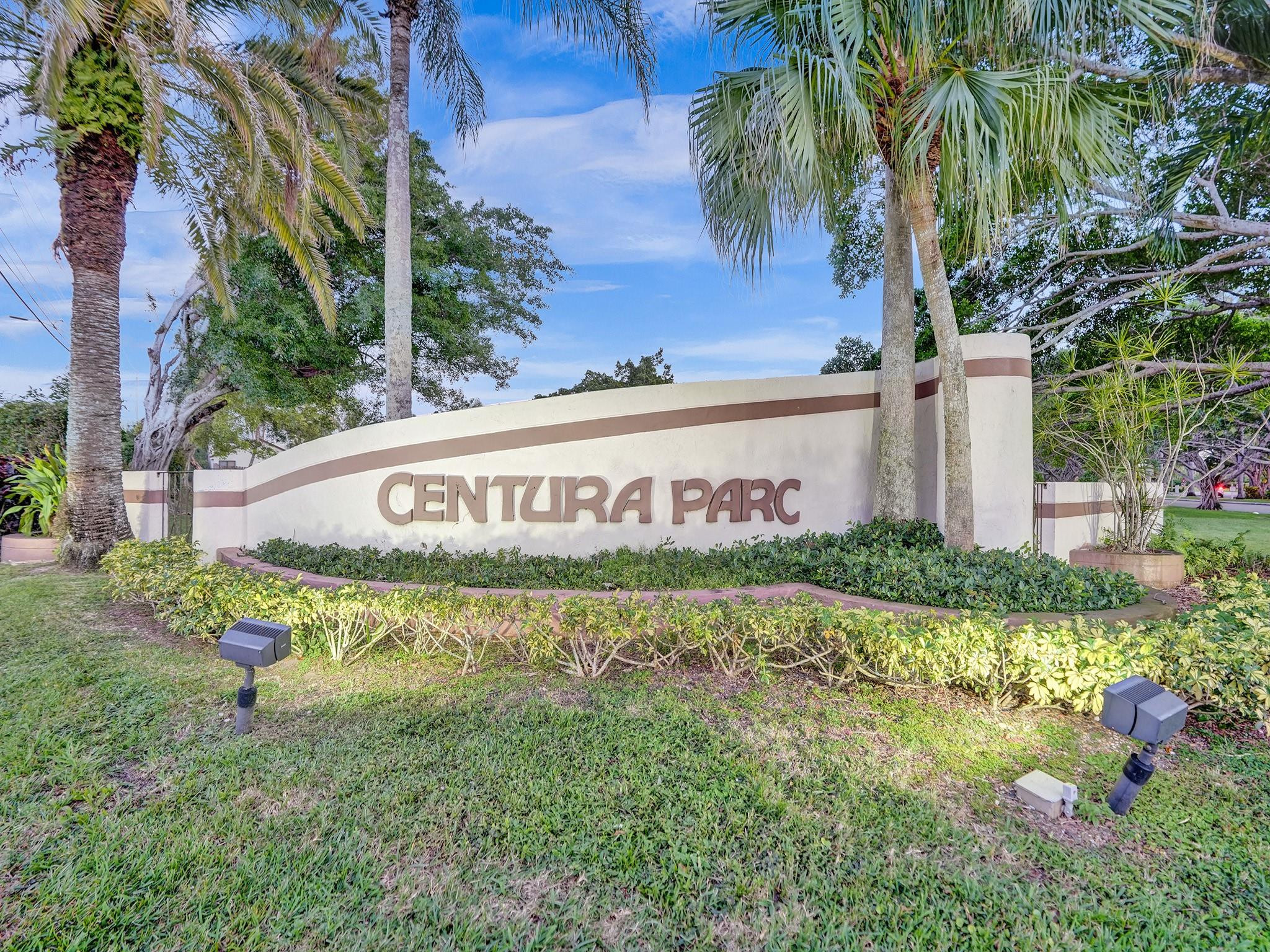 Centura Parc community entrance sign framed by palm trees and landscaping.