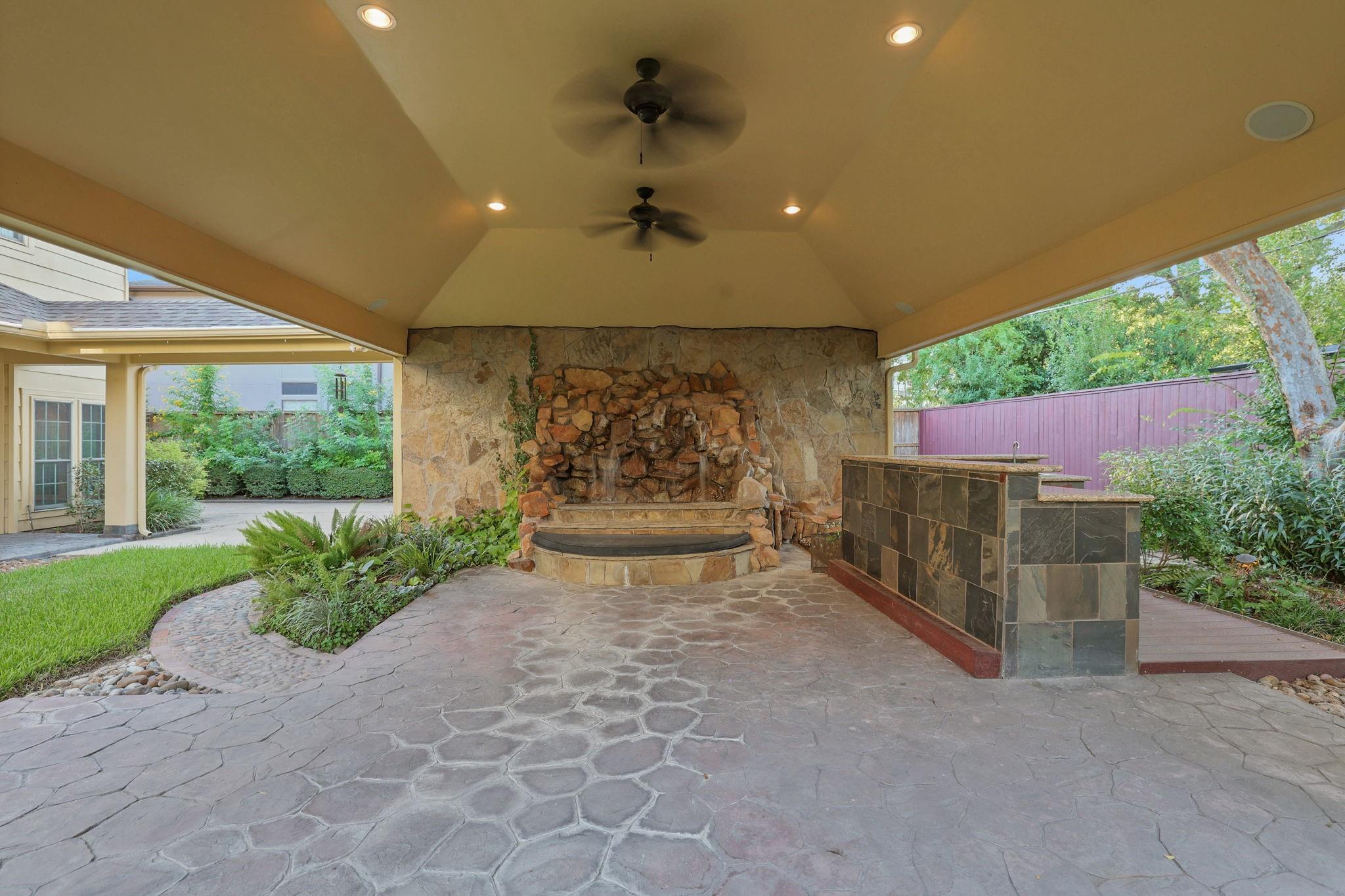 Covered patio with a stone fireplace, built-in counter, and flagstone flooring.