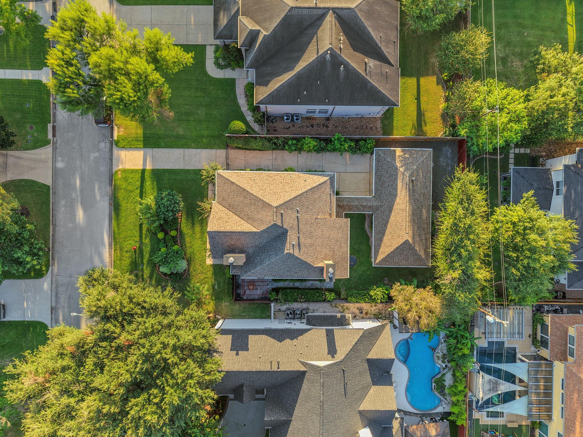 Aerial view of a house, landscaped yard, and surrounding homes.