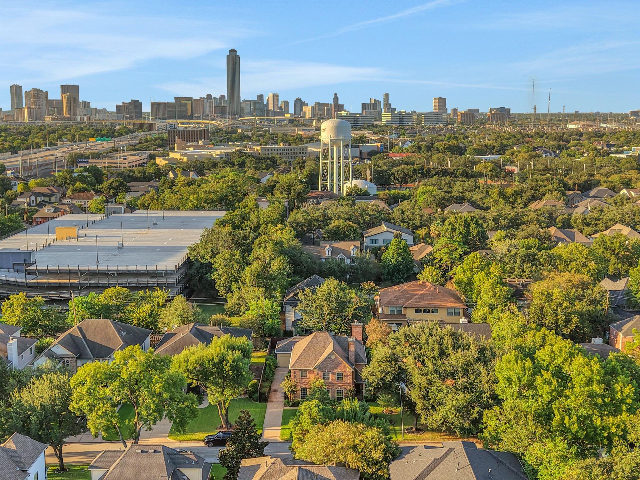 Aerial view of a leafy Bellaire neighborhood with Houston’s skyline and a water tower.