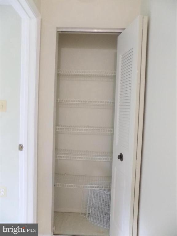 Empty closet with multiple wire shelves and an open louvered door.