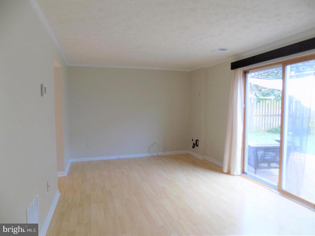 Vacant living room with light wood floors and a sliding glass door to a fenced patio.