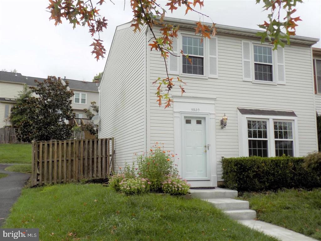 White-sided two-story home with shuttered windows, a front garden, and a walkway to the entrance.