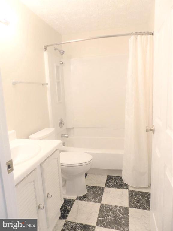 Bathroom with a white vanity, tub and shower, and black-and-white checkerboard floor.