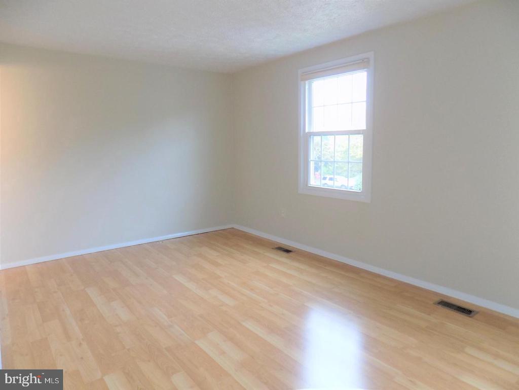 Empty room with pale wood flooring, neutral walls, and a white-trimmed window.