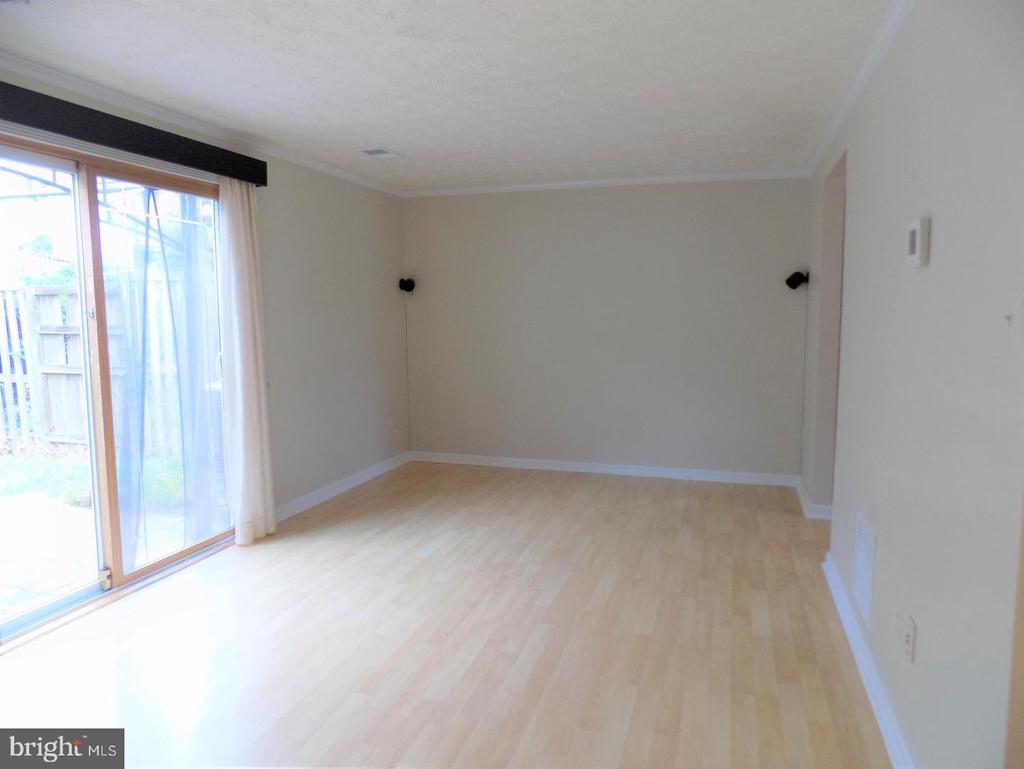 Empty room with light wood flooring and a sliding glass door to the yard.