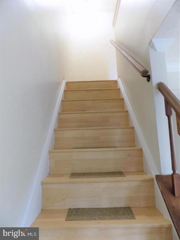 Light wood staircase with beige treads and a wooden handrail.