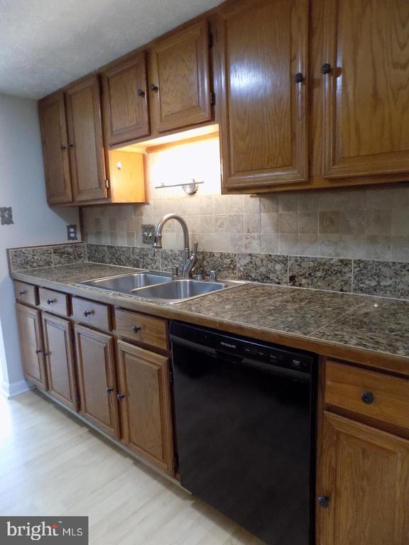 Kitchen with oak cabinets, granite counters, a double-basin sink, and a black dishwasher.