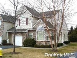 Two-story house with stone accents, an attached garage, and leafless trees in the front yard.