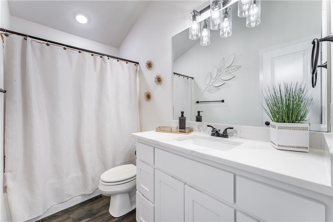 Bright bathroom with a white vanity, large mirror, and white shower curtain.