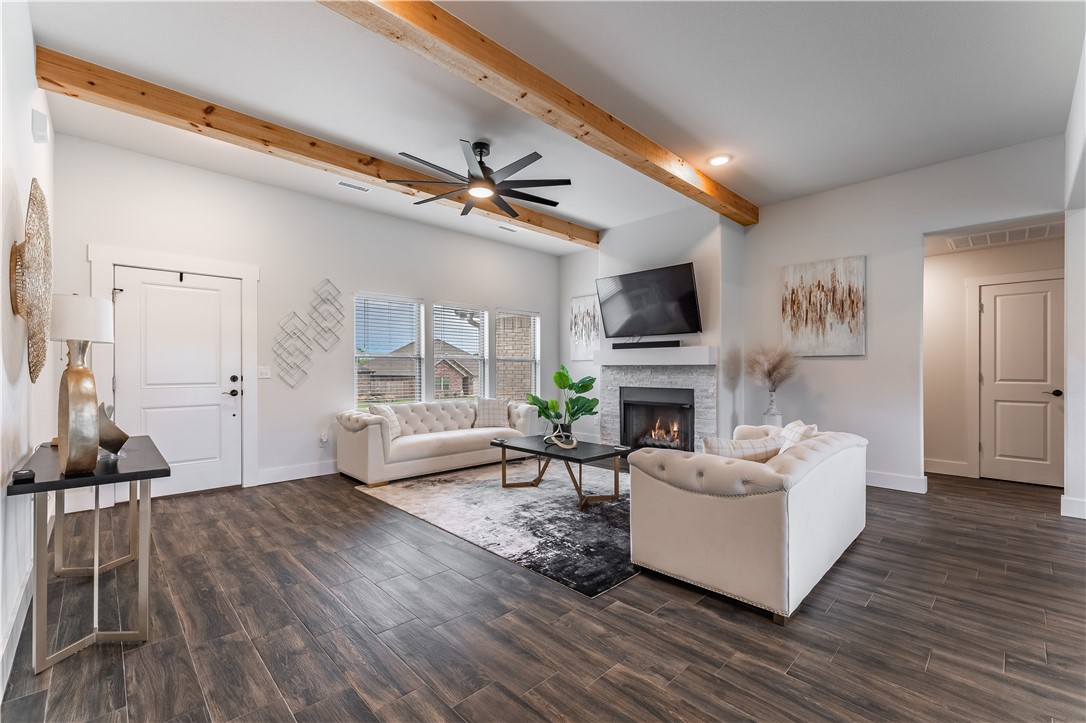 Living room with white sofas, a fireplace, and exposed wood ceiling beams.