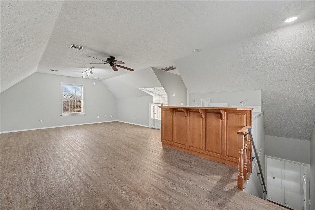 Open loft kitchen with wood flooring, vaulted ceiling, and a large wooden island.