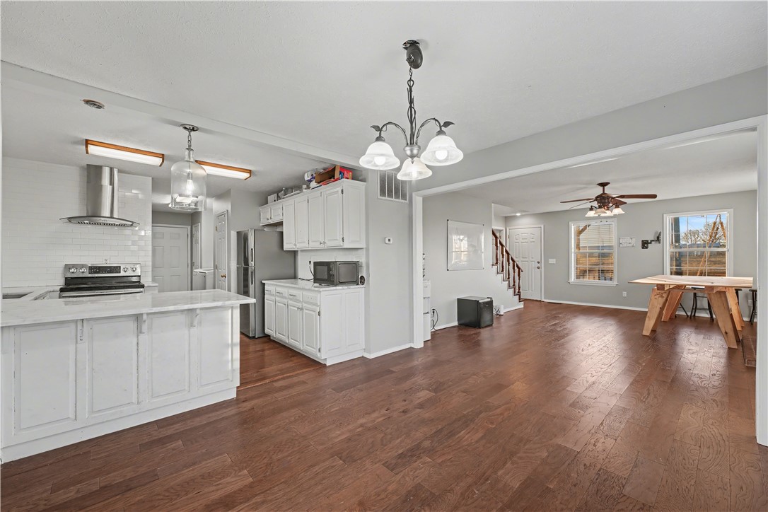 Open-plan kitchen and dining area with white cabinets, a large island, and dark hardwood floors.