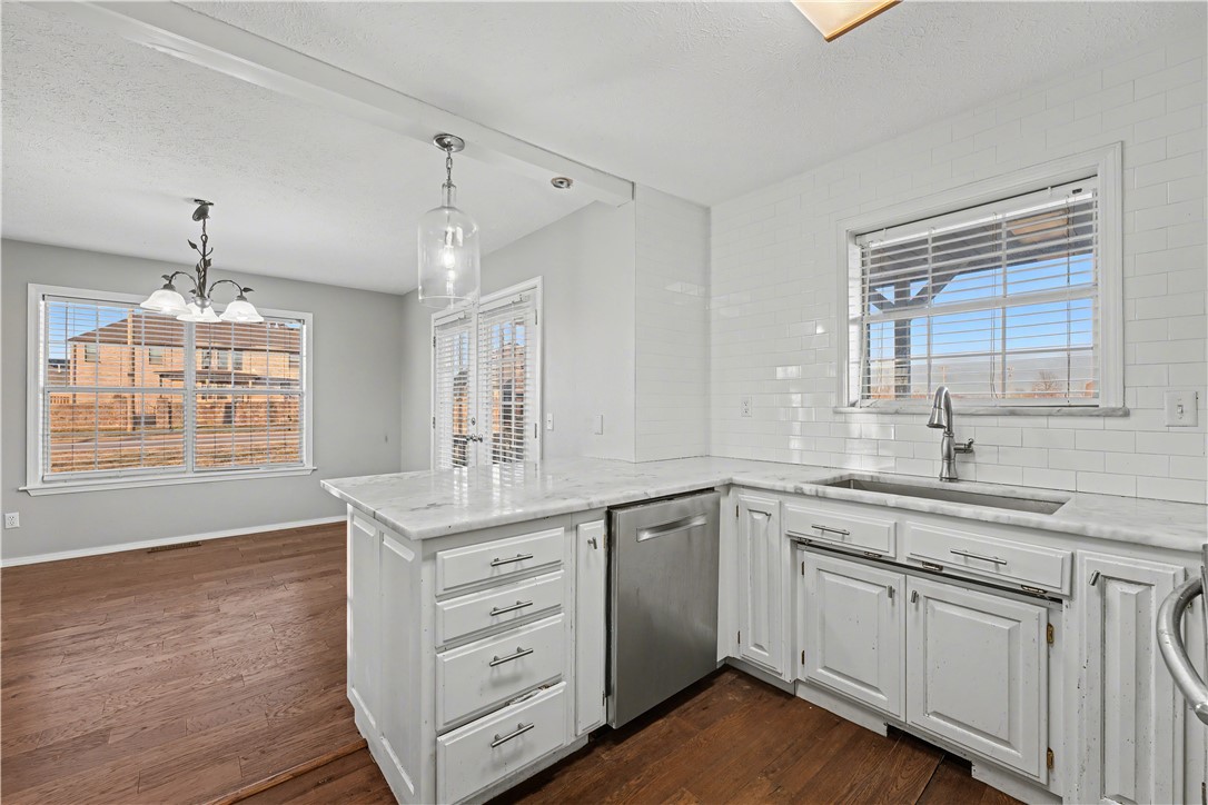 Kitchen with white cabinets, marble-look counters, a central island, and hardwood floors.