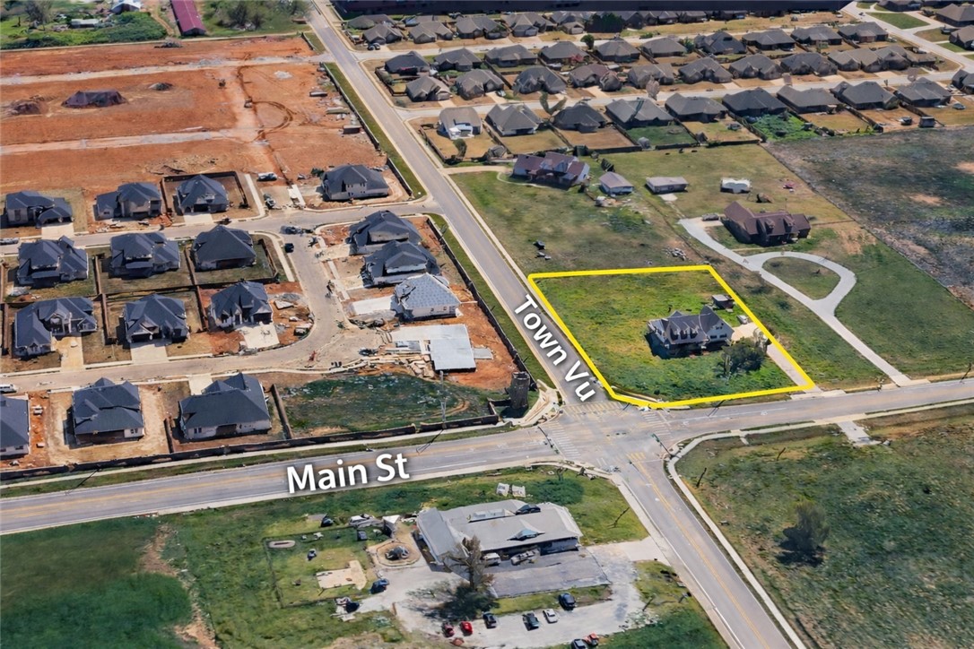Aerial view of a yellow-outlined corner lot with a house beside Main St and Town Vu.