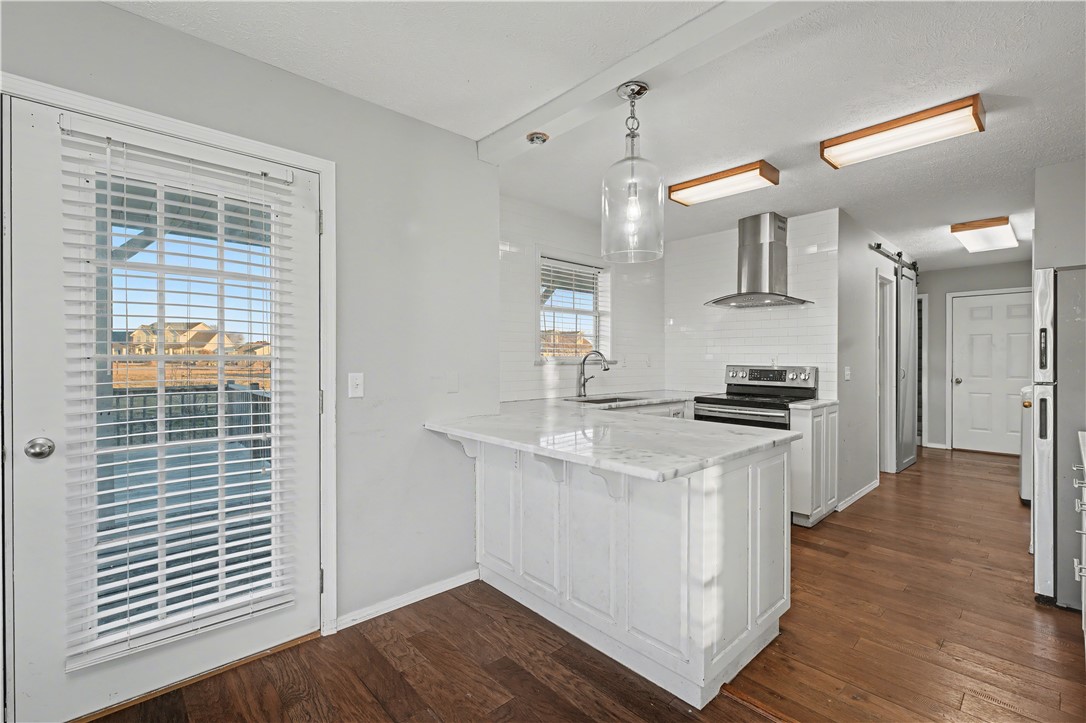 Kitchen with a white island, stainless steel appliances, and a glass-paneled door overlooking nearby homes.