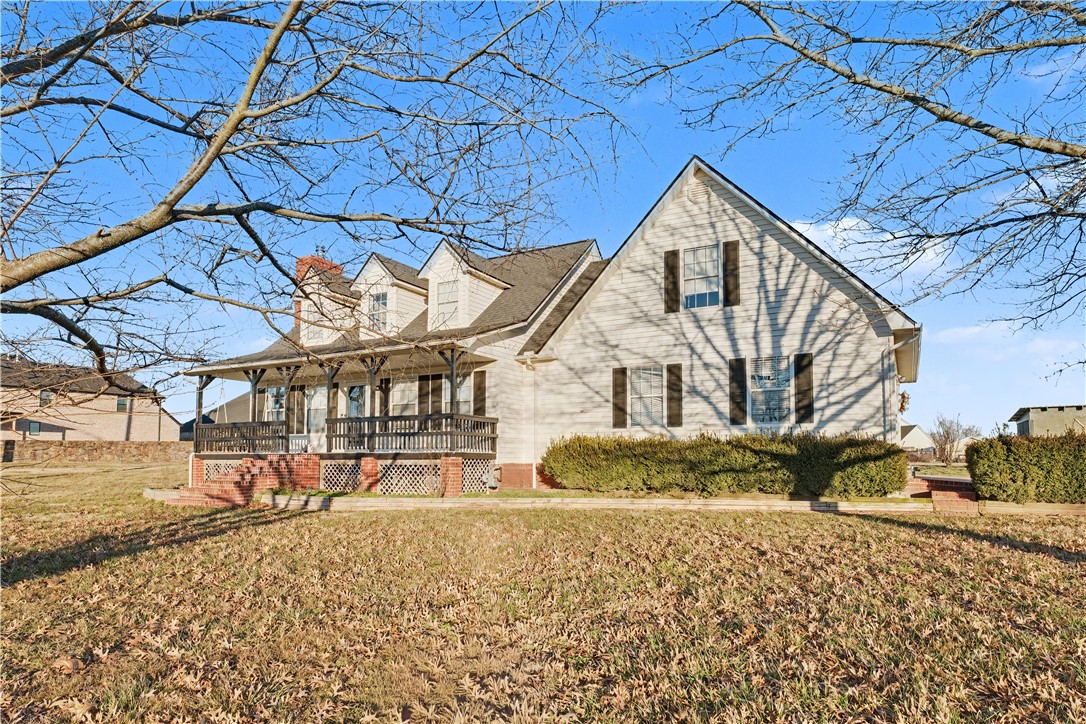 Light-colored house with a covered porch, brick steps, and leafless trees framing the front yard.