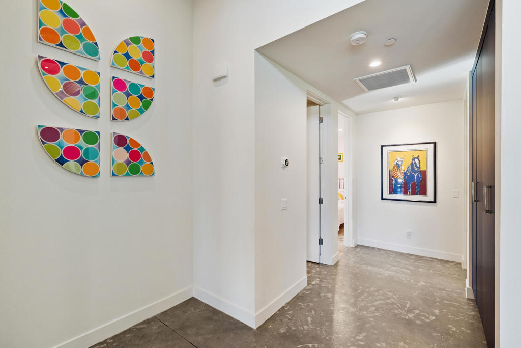 Bright hallway with colorful geometric wall art, a stone floor, and a framed print.