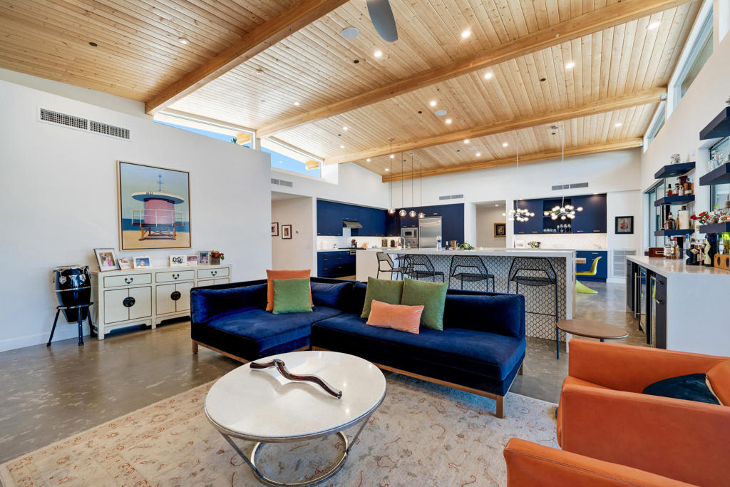 Open living room and kitchen with a vaulted wood ceiling, large island, and blue sofas.