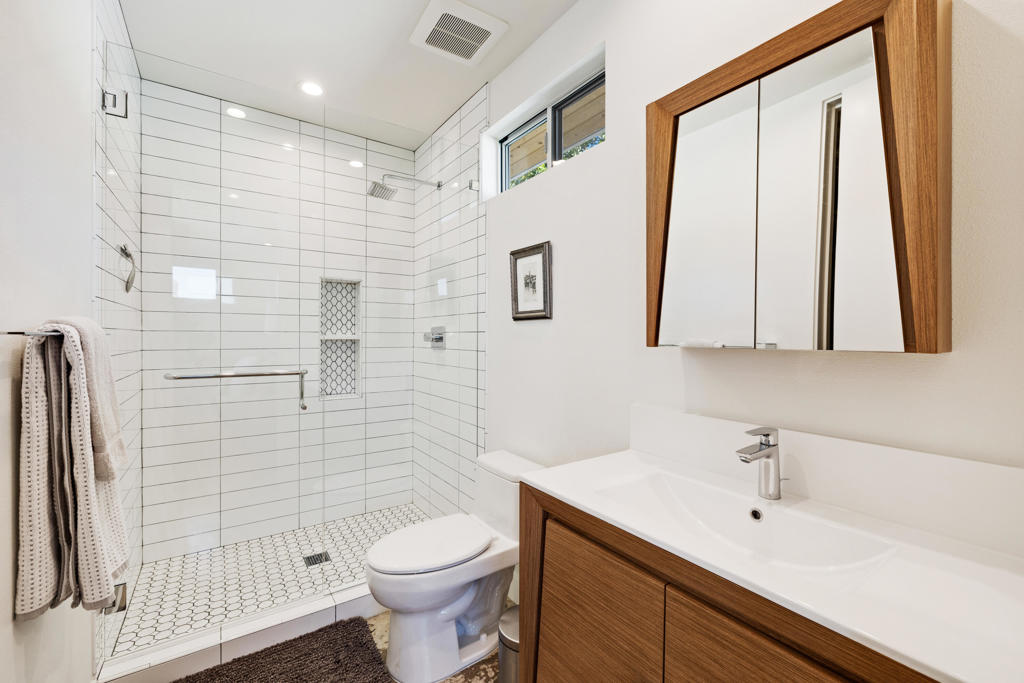 Modern bathroom with a white tiled walk-in shower and wood-front vanity.