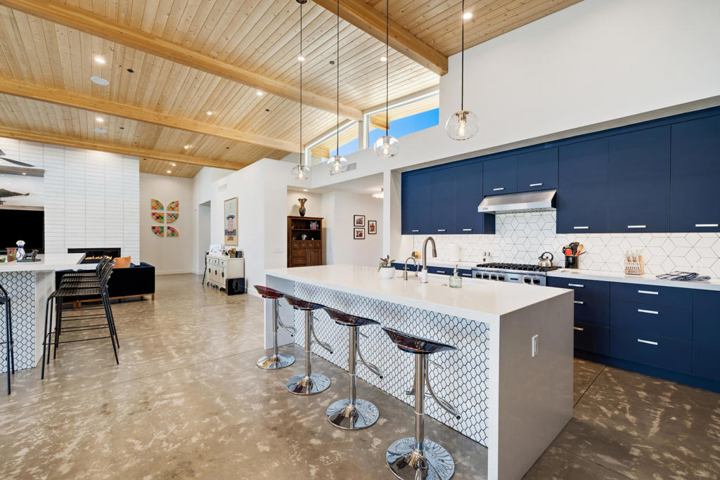 Kitchen with dark blue cabinets, a white island, and a vaulted wood-plank ceiling.