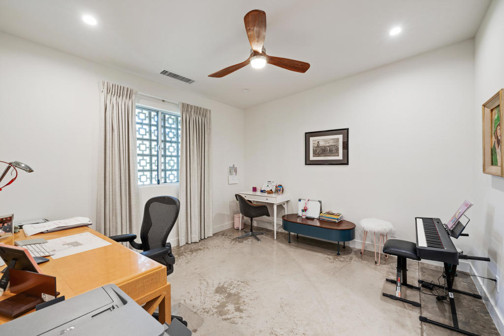 Multipurpose room with two work areas, a keyboard, and a patterned window screen.