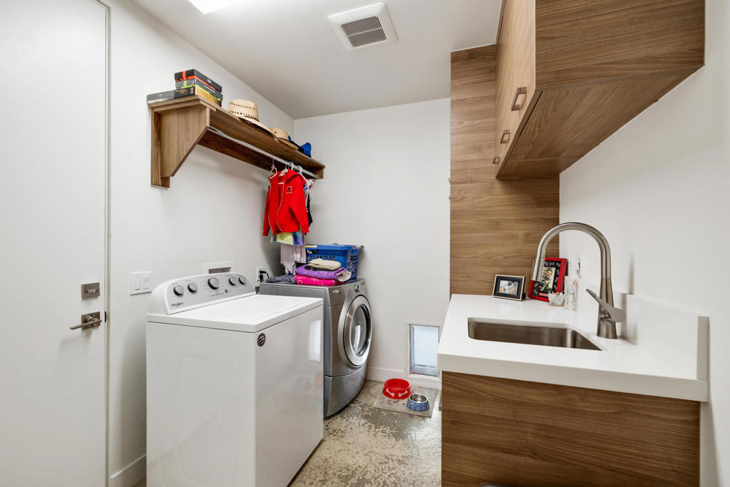 Laundry room with washer, dryer, and a wood-finished sink vanity.