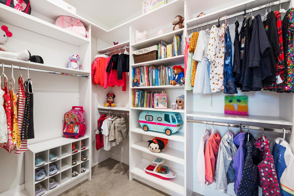 Built-in closet with children’s clothes, shoe cubbies, books, toys, and a turquoise toy camper.