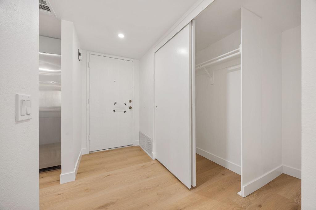 Entry hall with an open closet, white front door, and light wood flooring.