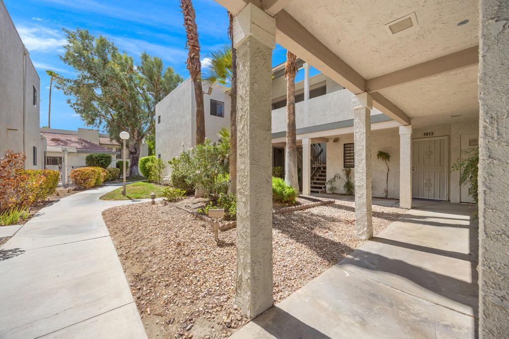 Residential courtyard with covered walkways, desert landscaping, and a winding concrete path.