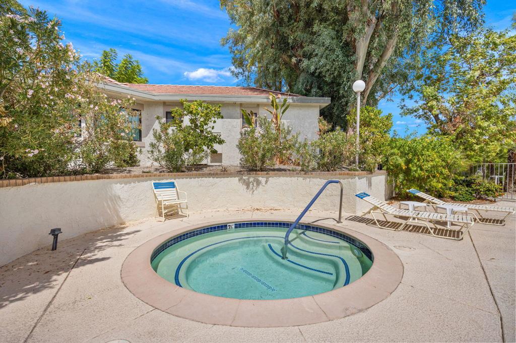 Circular backyard pool with a metal handrail, lounge chairs, and a single-story home behind it.