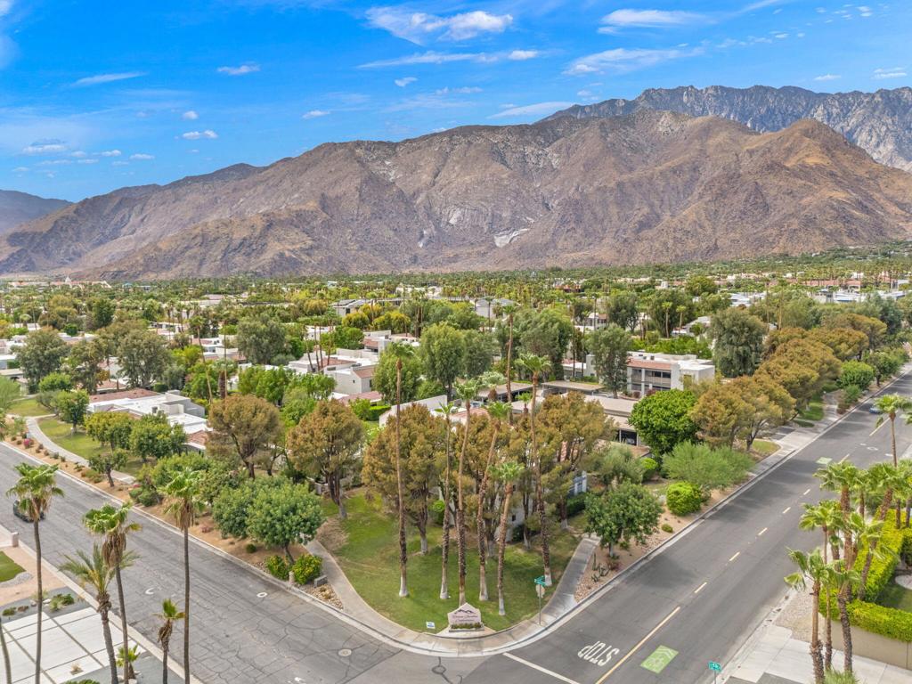 Aerial view of Palm Springs homes and streets with rugged mountains behind them.