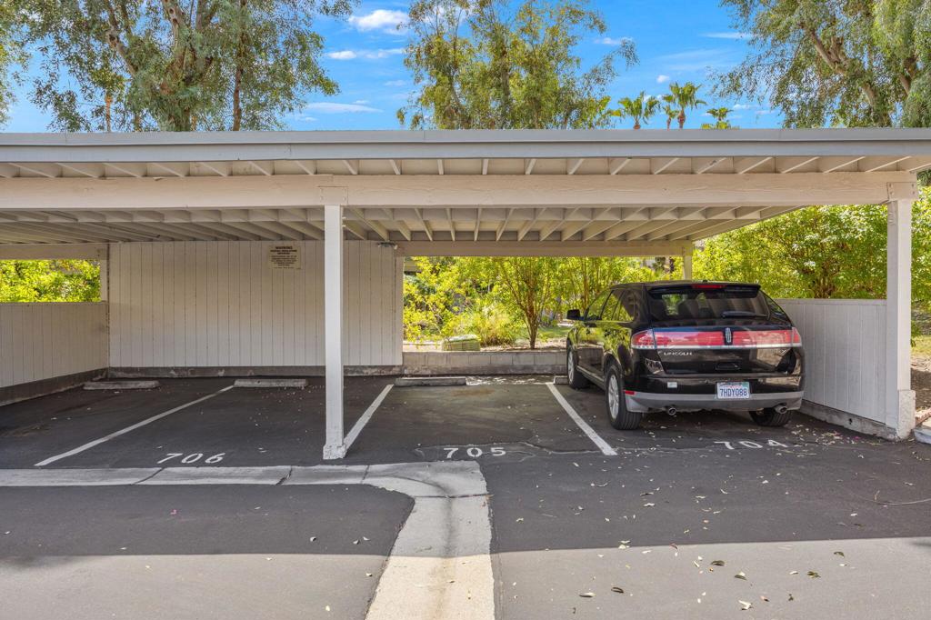 Covered parking spaces numbered 704–706, with a black Lincoln parked in one.
