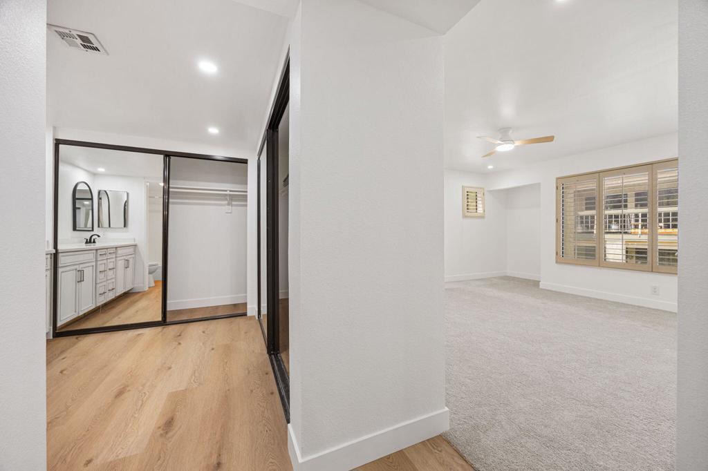 Unfurnished bedroom with plantation-shuttered windows, beside a mirrored closet and vanity.